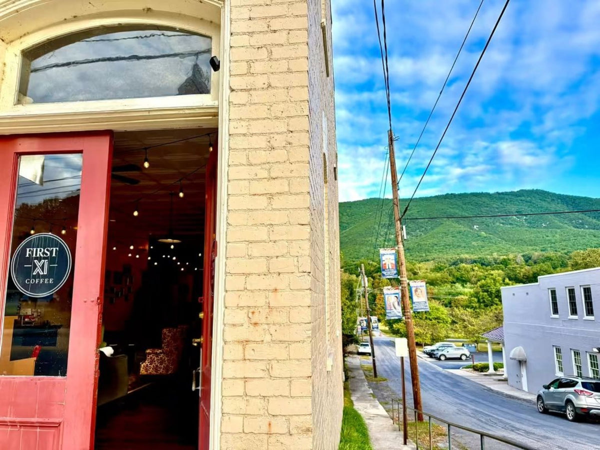 First XI Coffee storefront with a red door and mountain view